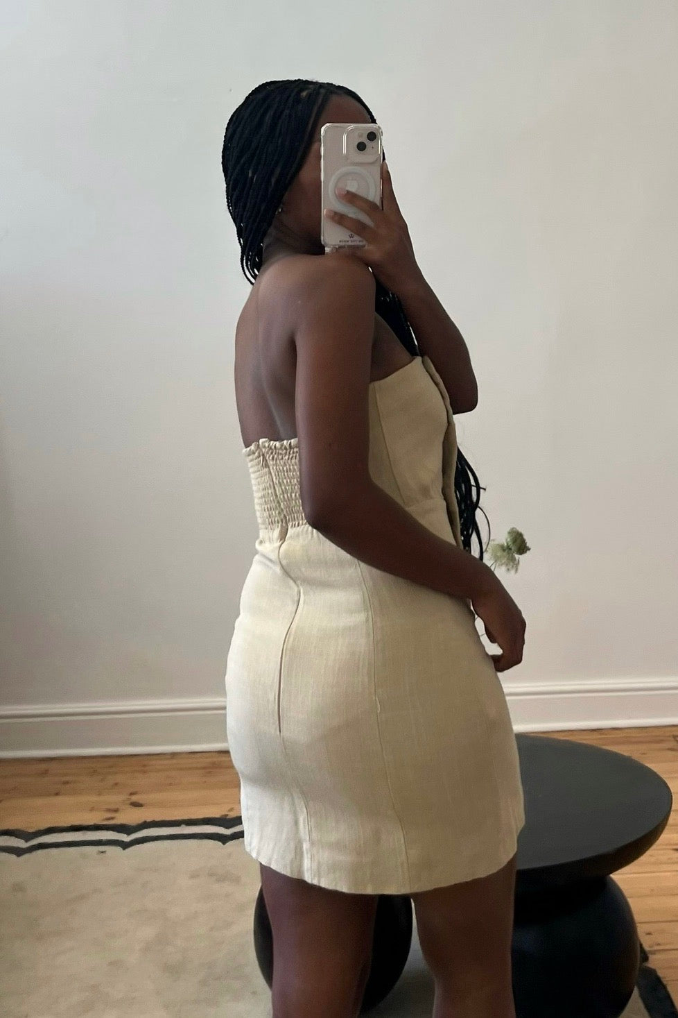 A person wearing a beige mini dress with a button front placket and smock detail at the back, made from 100% viscose fabric.