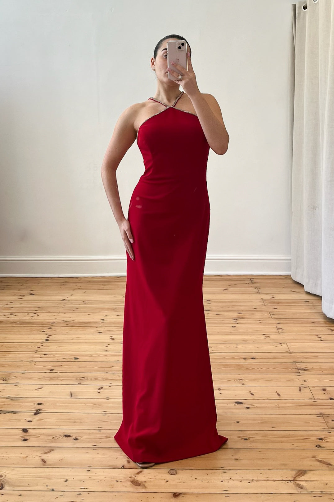 Model wearing The Mallon Gown – a red, floor-length halter neck dress with built-in cups, styled for a formal occasion. Pre-loved, size small (UK8), available on Style Rotate SResale.