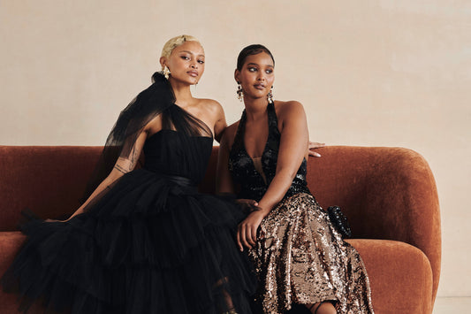 Two women dressed in elegant black and sequin gowns, representing premium styles available with dress rental near me.