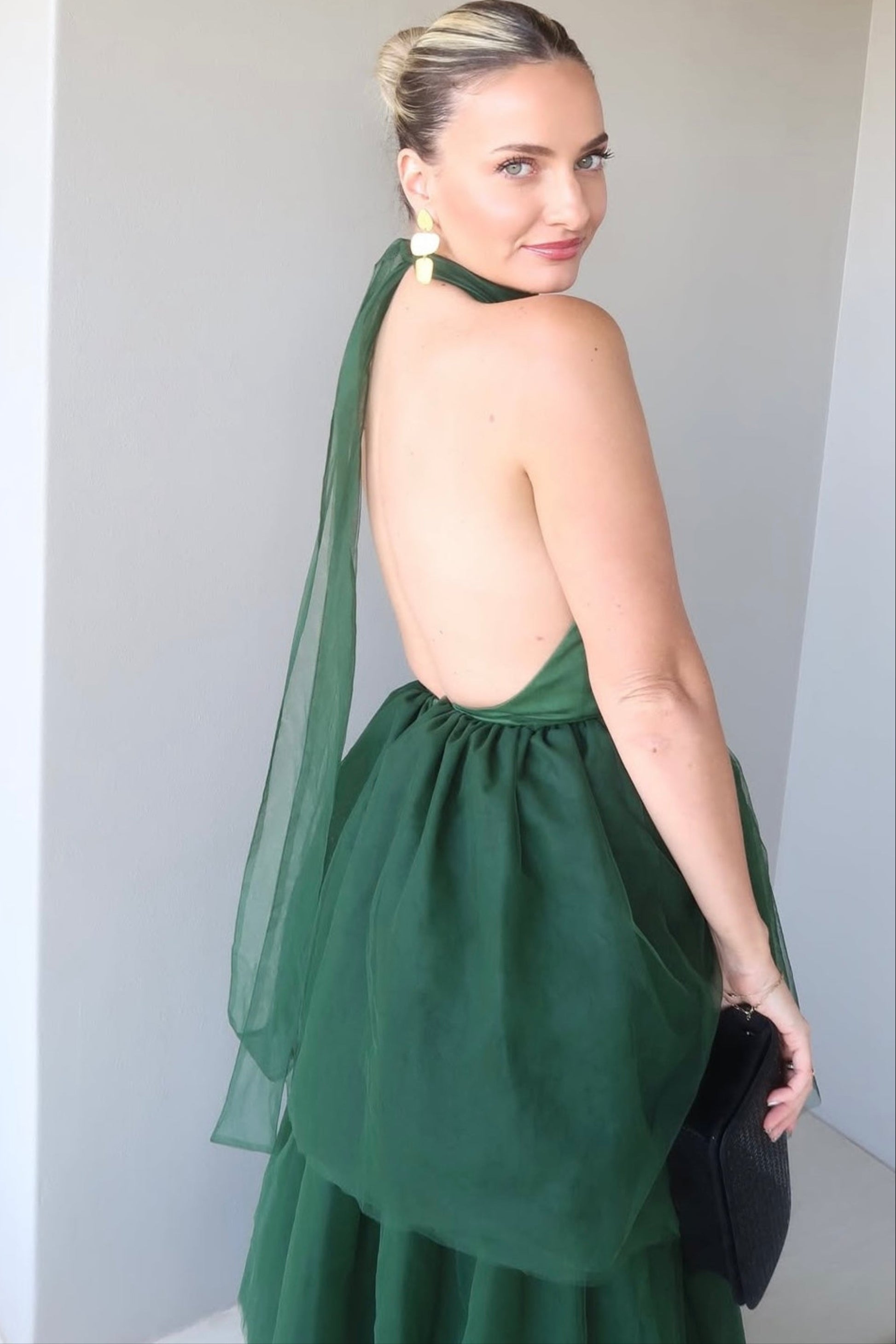 Woman wearing a green dress with a sheer overlay against a plain background