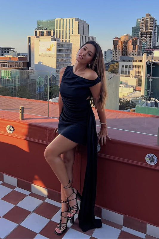 Woman in a black dress standing on a rooftop with cityscape in the background