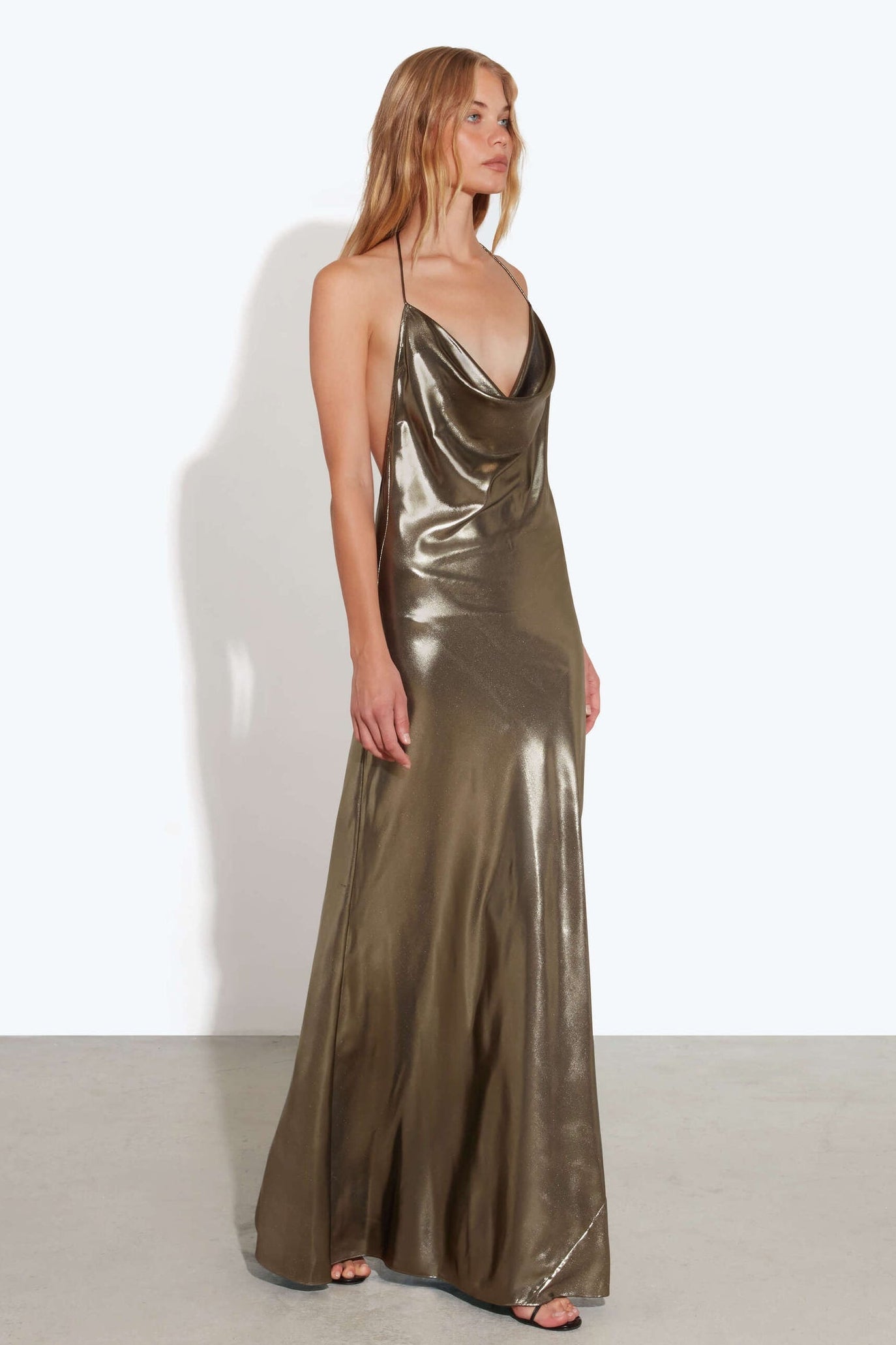 Woman wearing a metallic gold evening gown against a white background