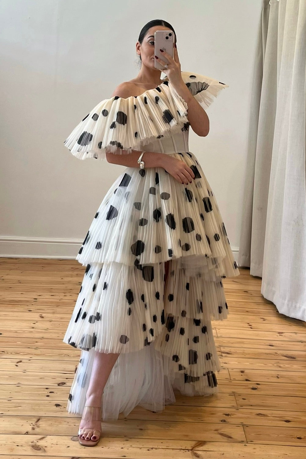 The Bradshaw Gown – a dramatic off-the-shoulder gown with micro pleats and a tiered skirt, perfect for formal occasions. Elegant, timeless, and available now.