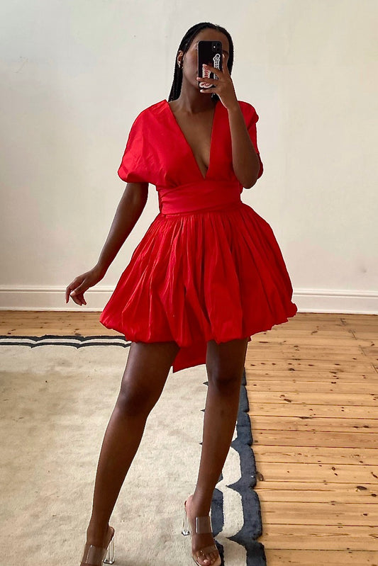 The Stella Mini by Kat Van Duinen – a red mini dress with a bubble hem skirt and tie waist belt, perfect for cocktail parties and festive events. Bold, chic, and available now for rental.