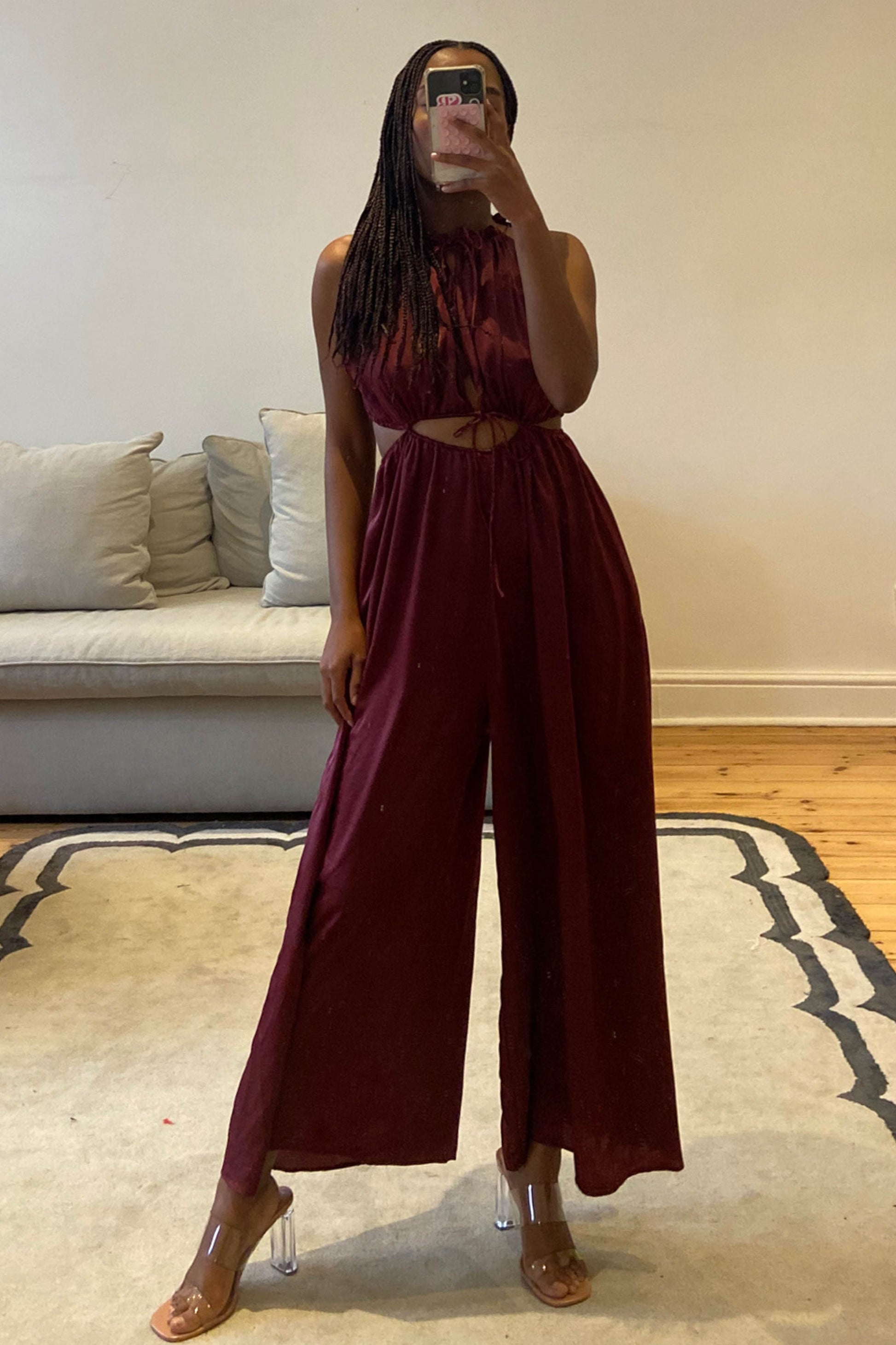Burgundy jumpsuit with high neckline and self-tie cut-out details at the waist