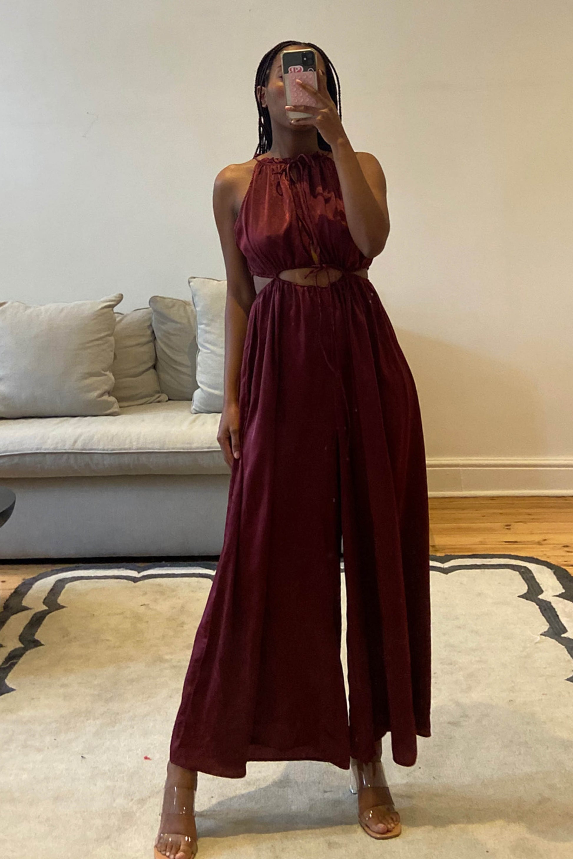 Burgundy jumpsuit with high neckline and self-tie cut-out details at the waist