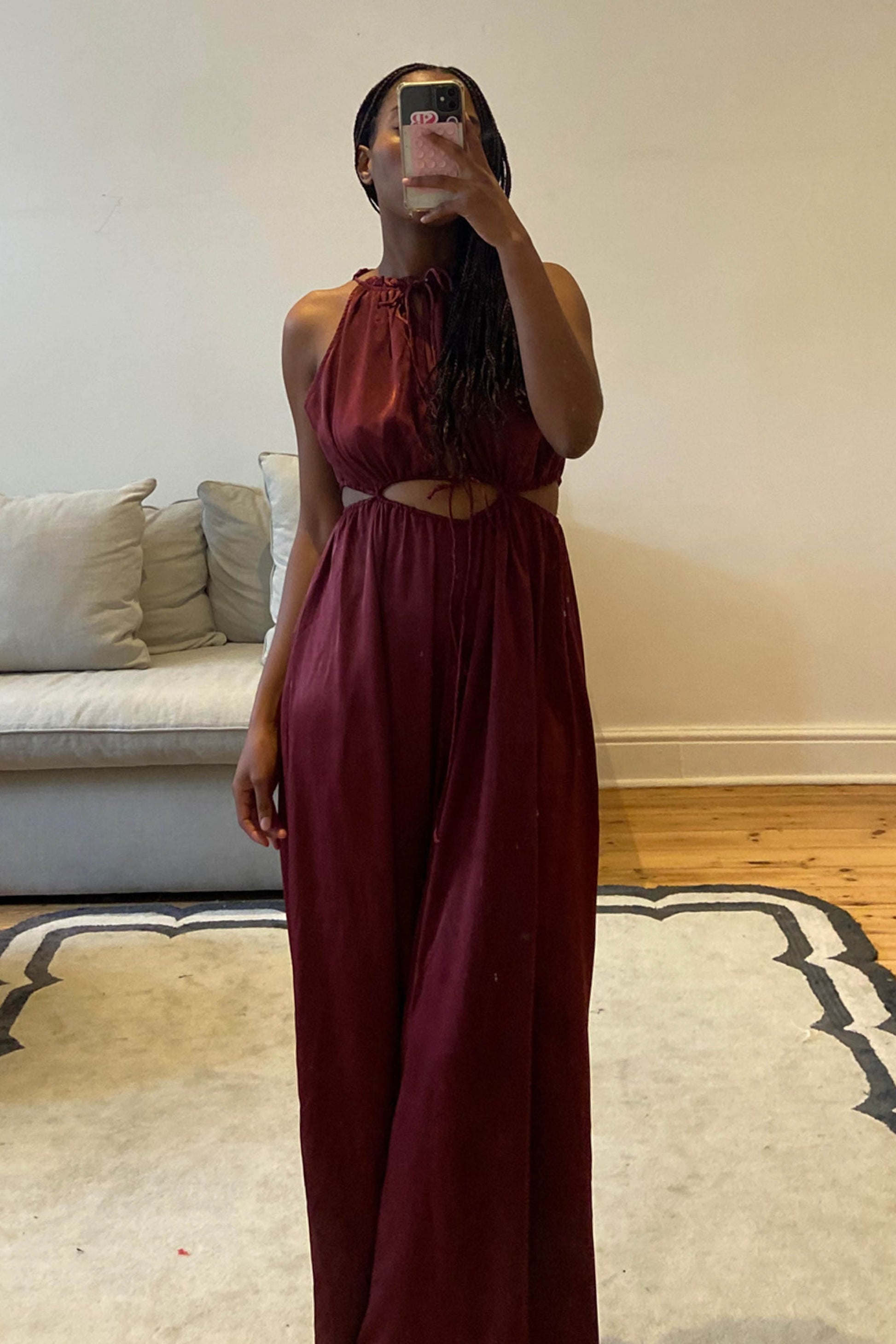 Burgundy jumpsuit with high neckline and self-tie cut-out details at the waist