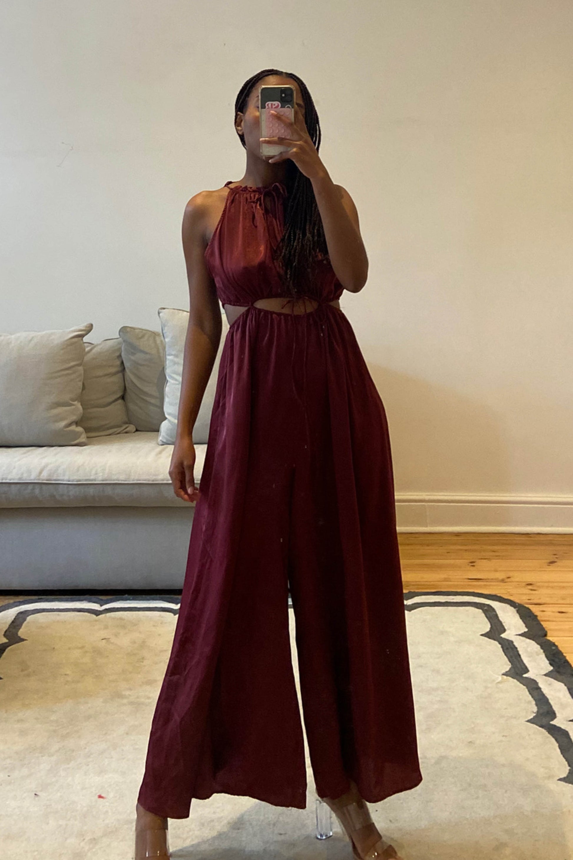 Burgundy jumpsuit with high neckline and self-tie cut-out details at the waist